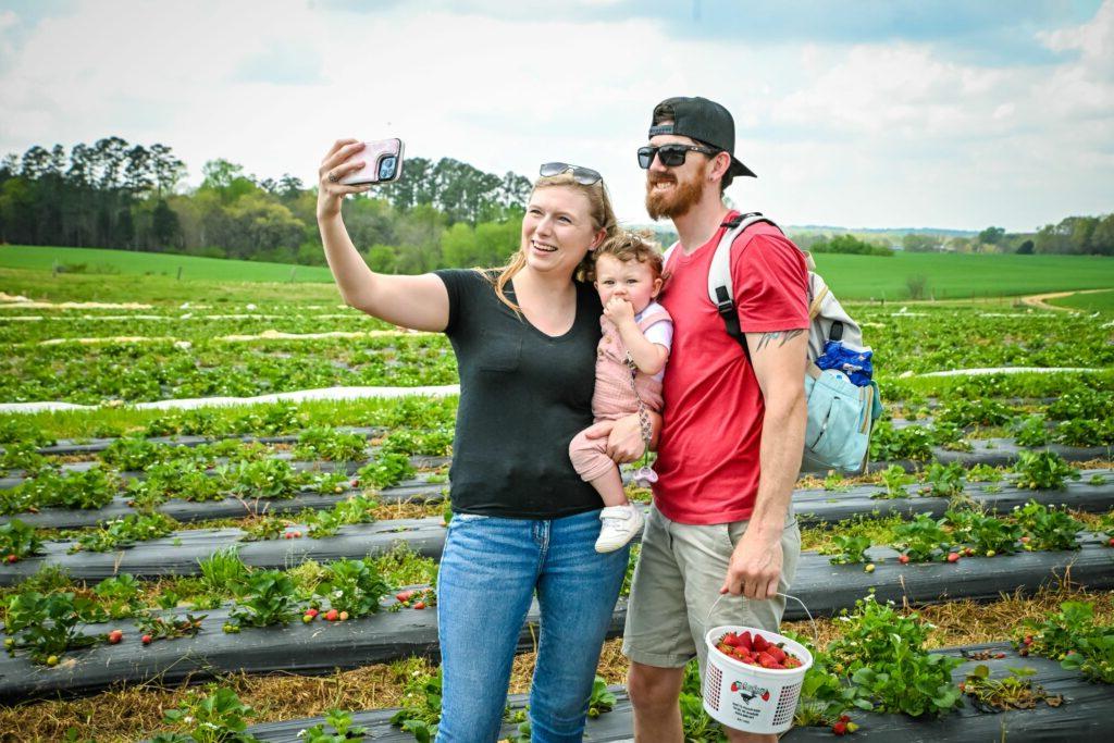 family takes a selfie picture in a strawberry field